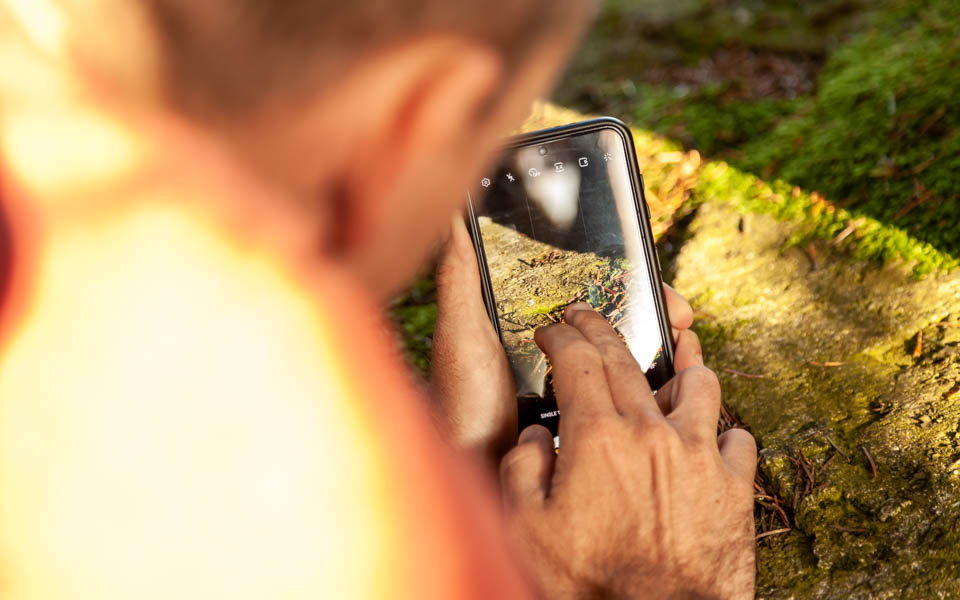 Un homme prend en photo de la mousse avec son téléphone portable