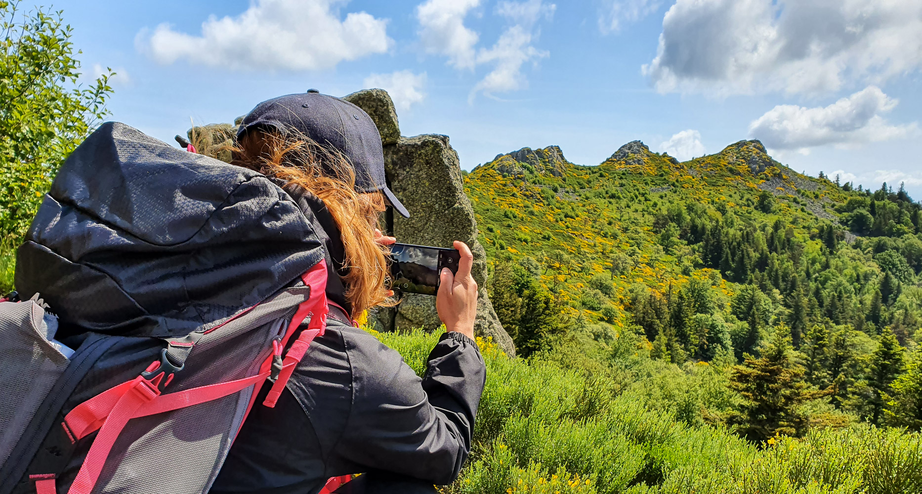 Une femme prend une photo des Trois Dents du massif du Pilat avec son smartphone