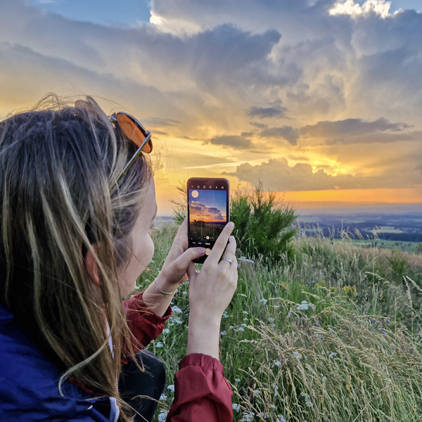 Une femme photographie un coucher de soleil lors d'un atelier photo nature dans le Parc Naturel du Pilat